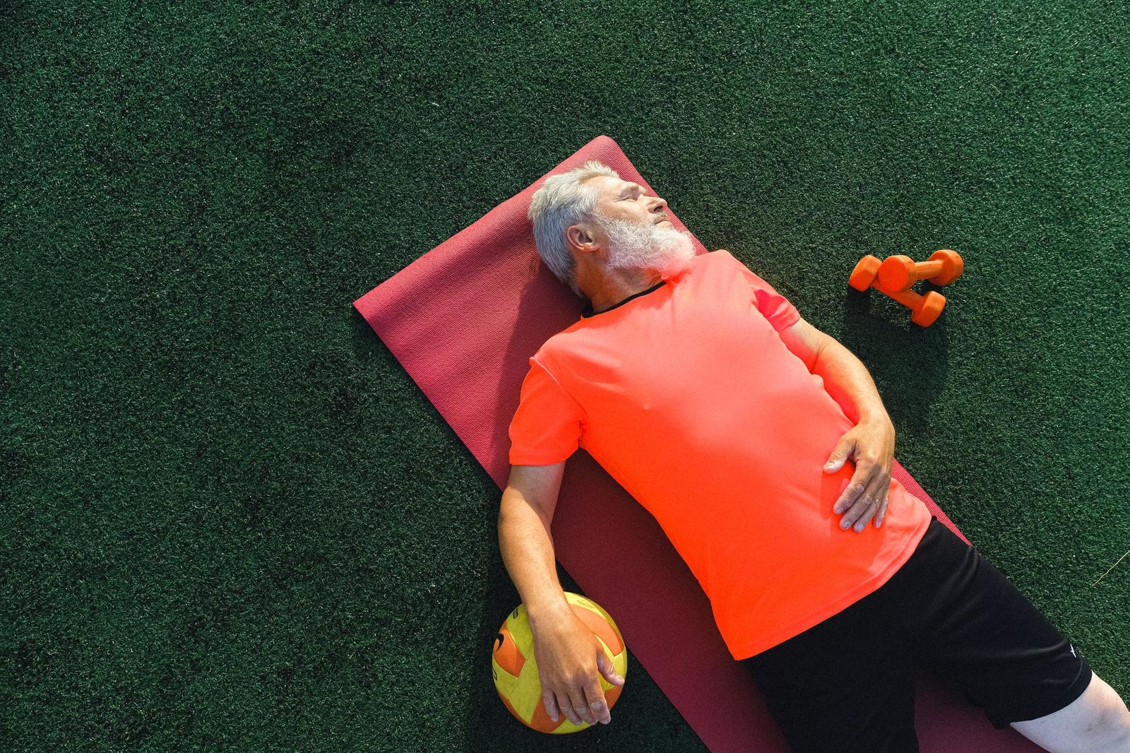 Elderly Sportsman Resting on Exercise Mat After Training